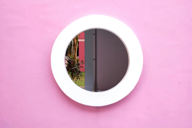 pink wall with white circular mirror on it