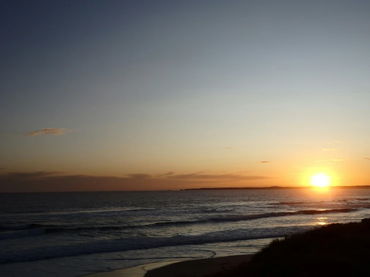 a beach with an ocean front at sunset