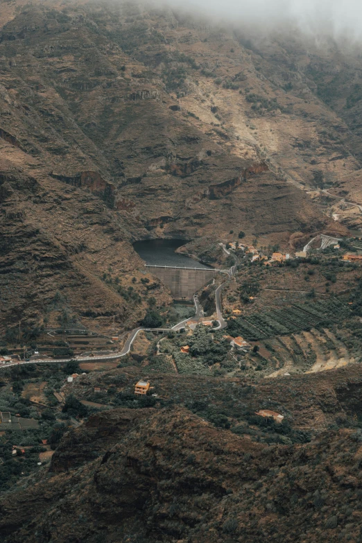 a road going between two mountains that have trees growing on them