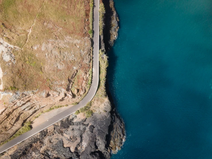 a winding road is on the side of an island near water