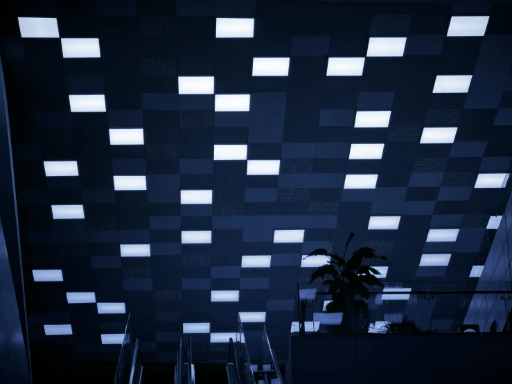 an escalator in front of a patterned ceiling