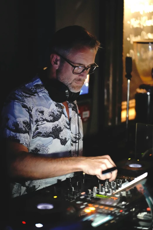 a man in glasses mixing music on a sound mixer