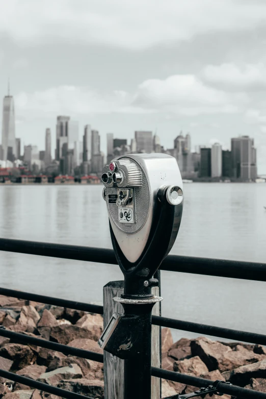 a silver and black coin operated binoculars in front of the city skyline