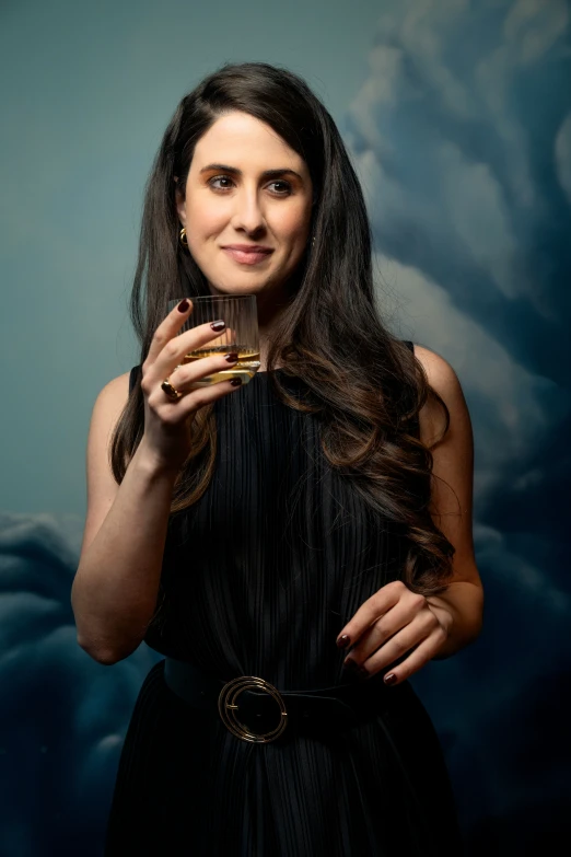 a woman in a dress is posing with a drink