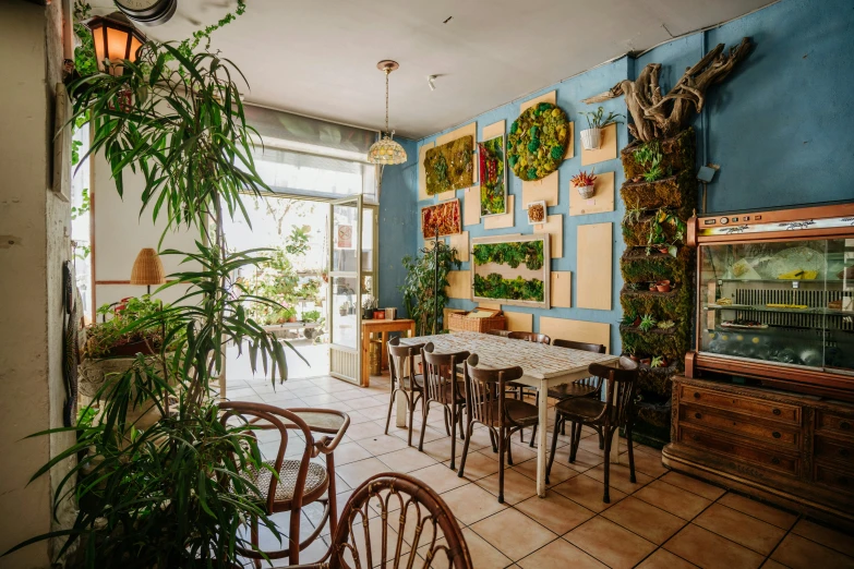 inside of an indoor cafe with tables, plants, and artwork on the walls