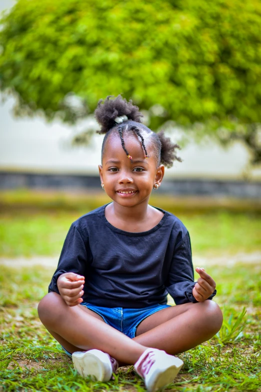 an adorable little girl sitting on the grass
