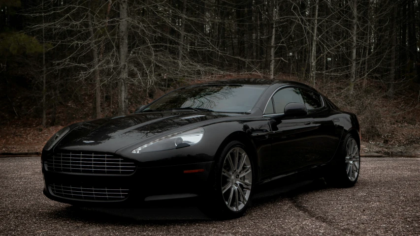 a black sport car parked on top of a gravel parking lot