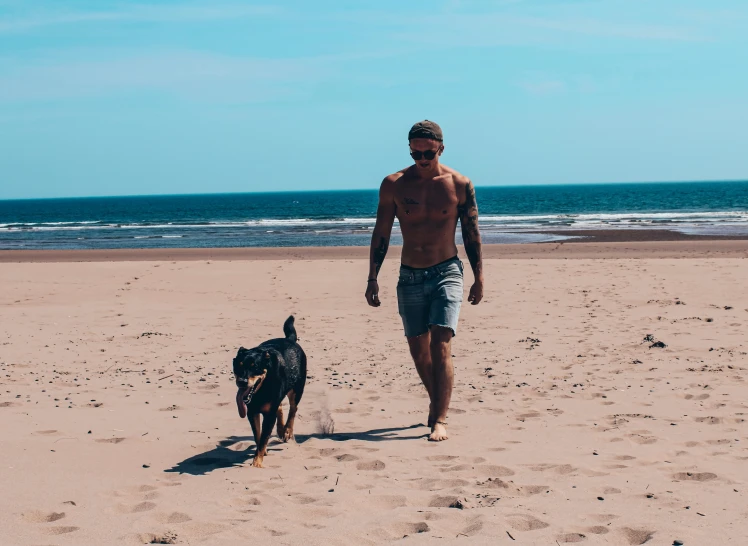 man walking down the beach with his dog