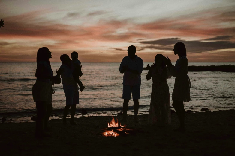 five friends gather near a fire on the beach