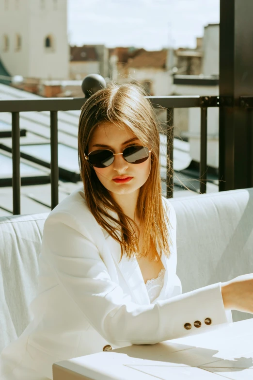 a woman wearing sunglasses sitting at a table on the balcony