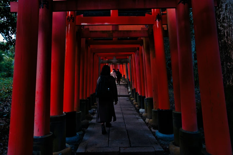 a woman walking down an alley lined with columns