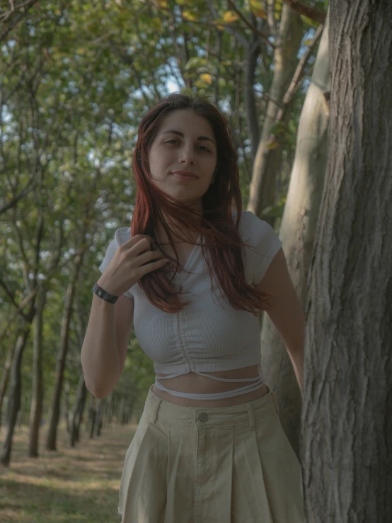 a woman standing in front of a tree with her hair up