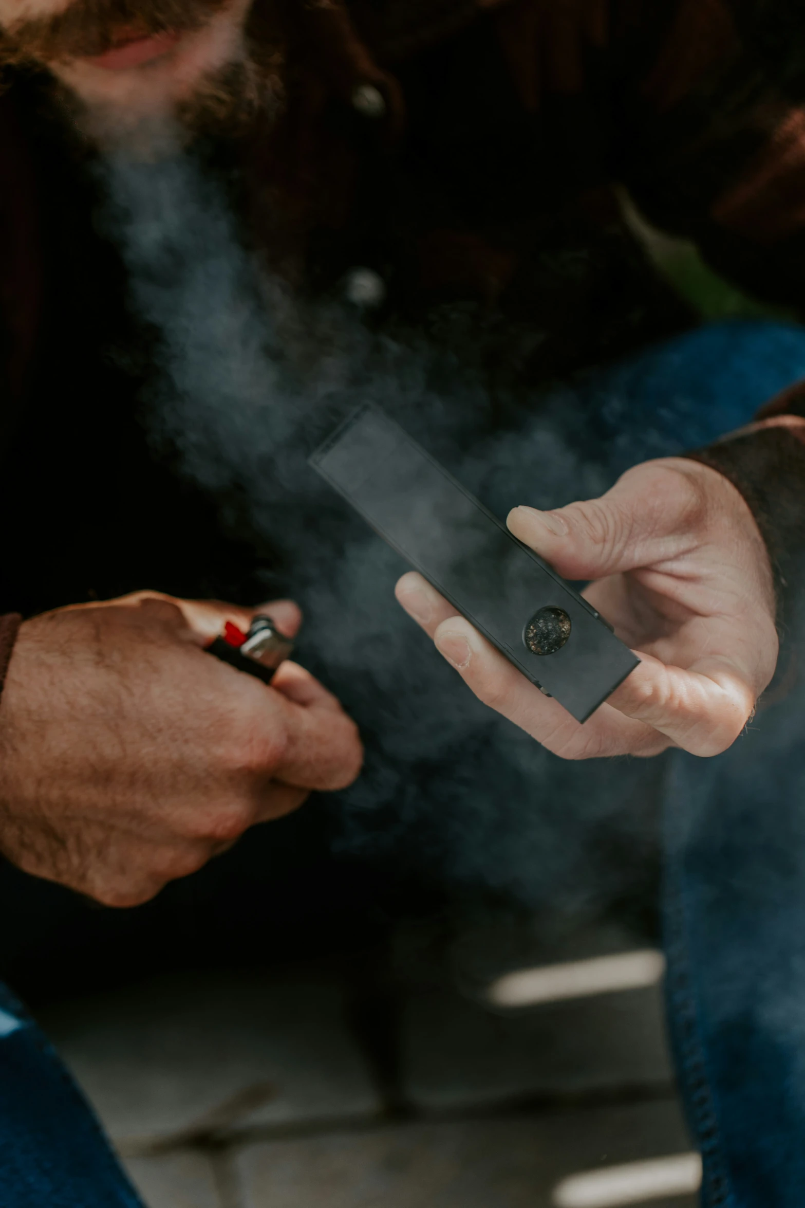 a man smoking a cigarette and using an electronic device