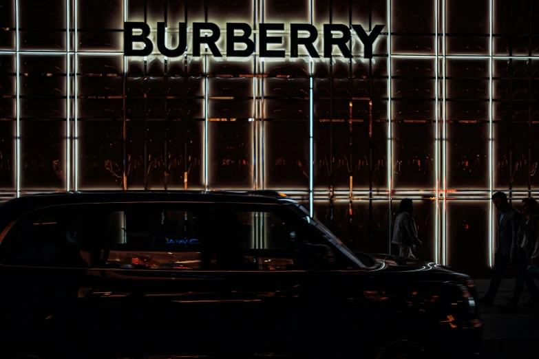 cars are driving down a dark street in front of a burberry sign