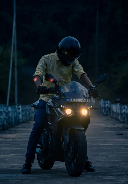 a man riding a motorcycle down a road next to a forest