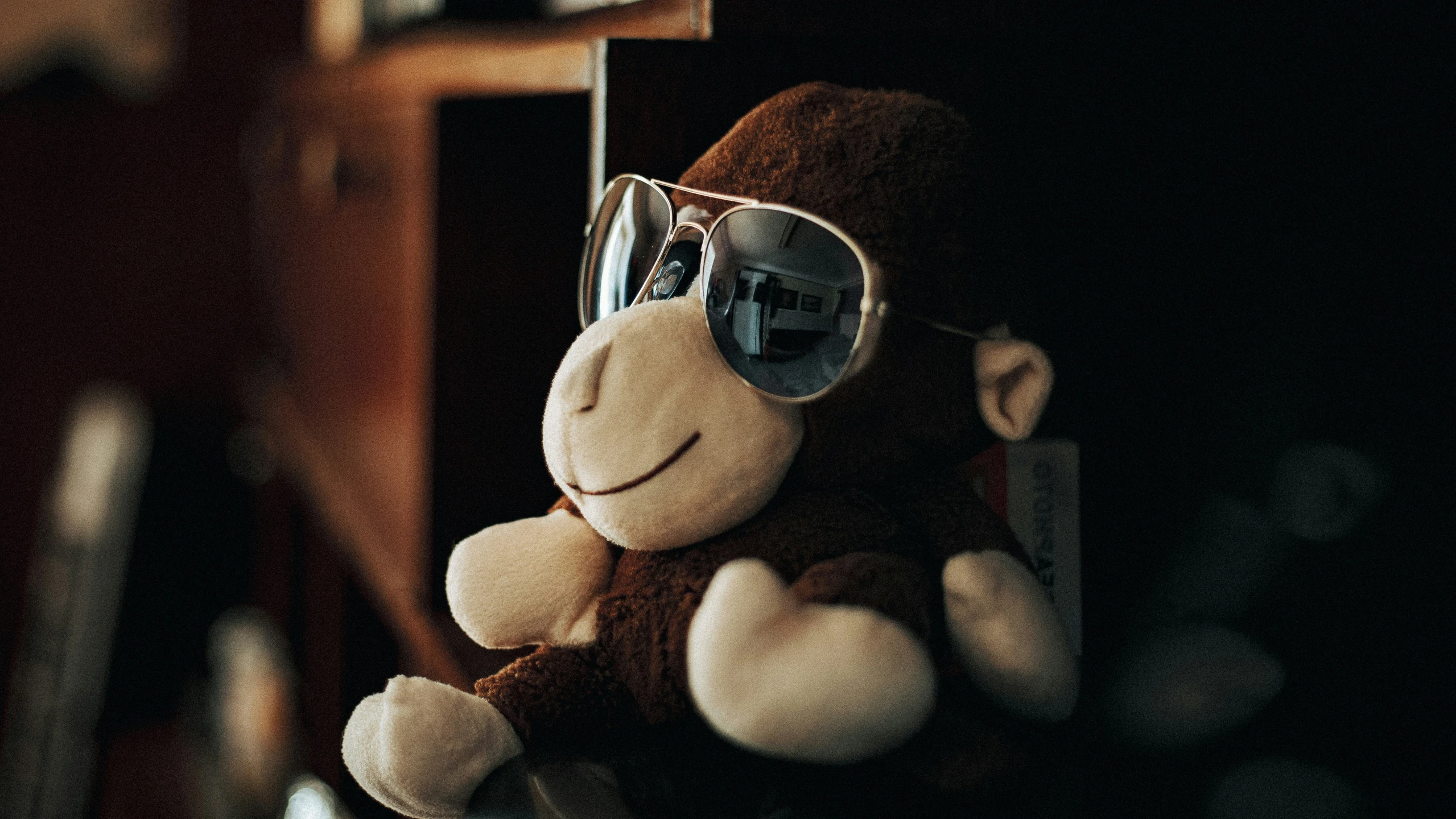 a stuffed monkey in sunglasses with a lamp next to it