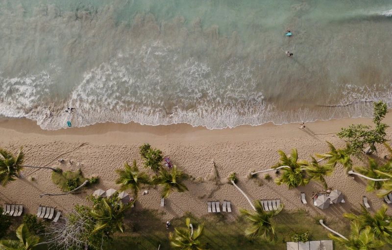 the beach with chairs and surfboards in the sand