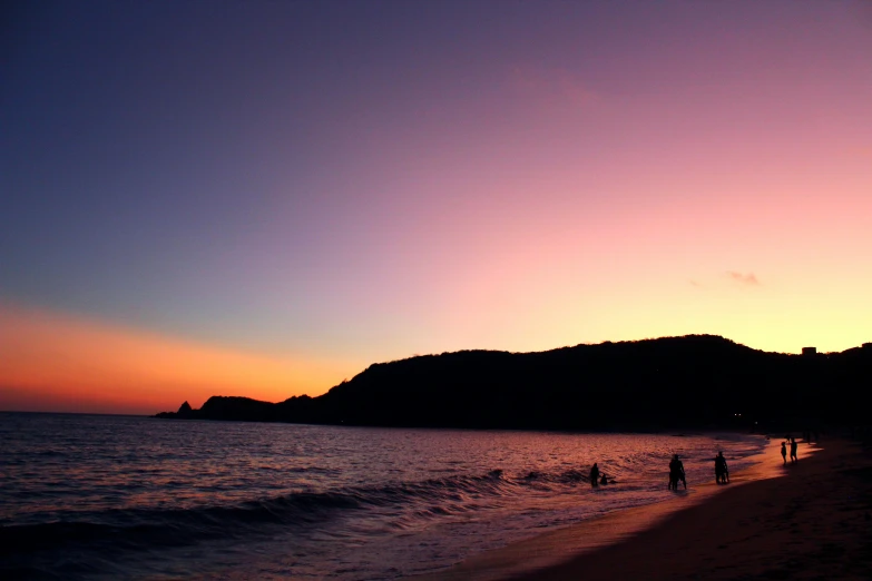 people are walking in the water at a beach