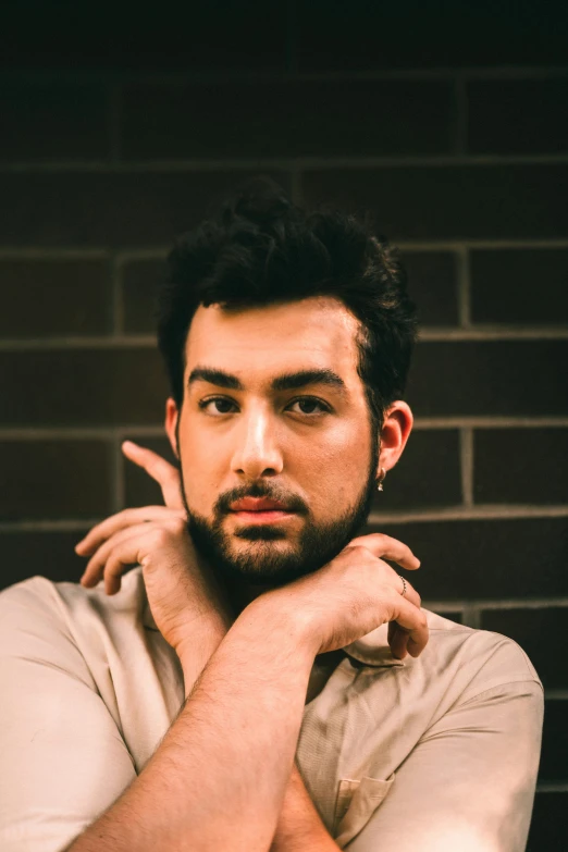 a man posing for a picture next to a brick wall