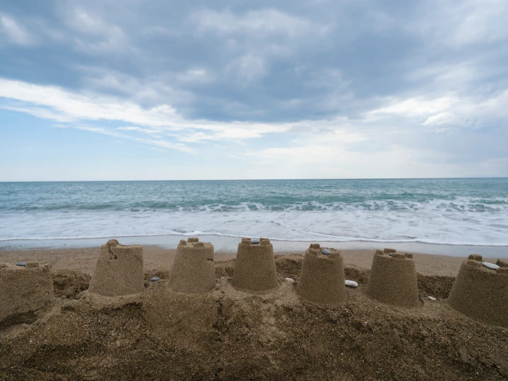 sand castle near ocean under cloudy blue sky