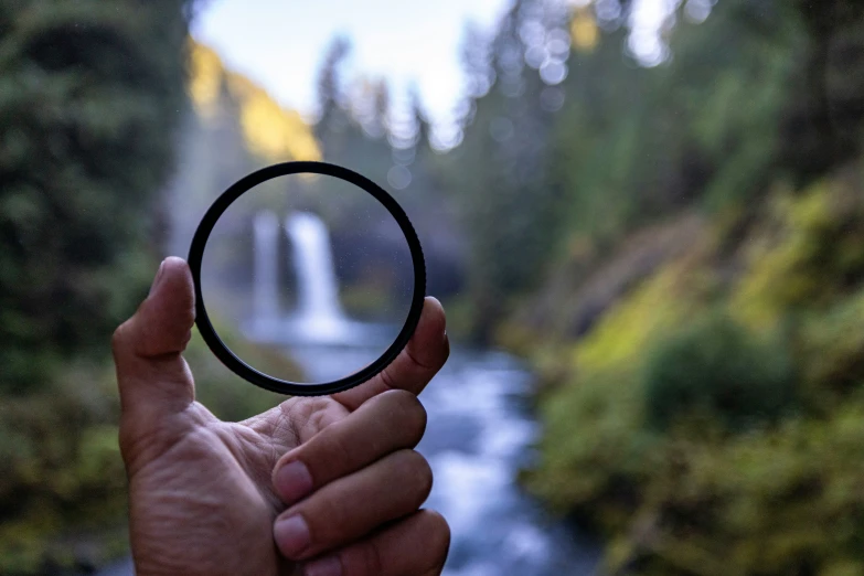 a hand is holding up a circular object above the water