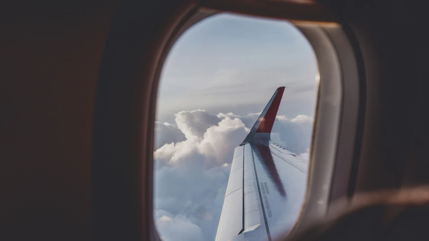 an airplane wing with a cloudy sky as seen from below