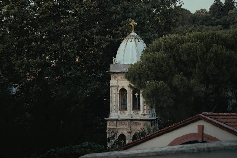 a church steeple with cross on top surrounded by trees