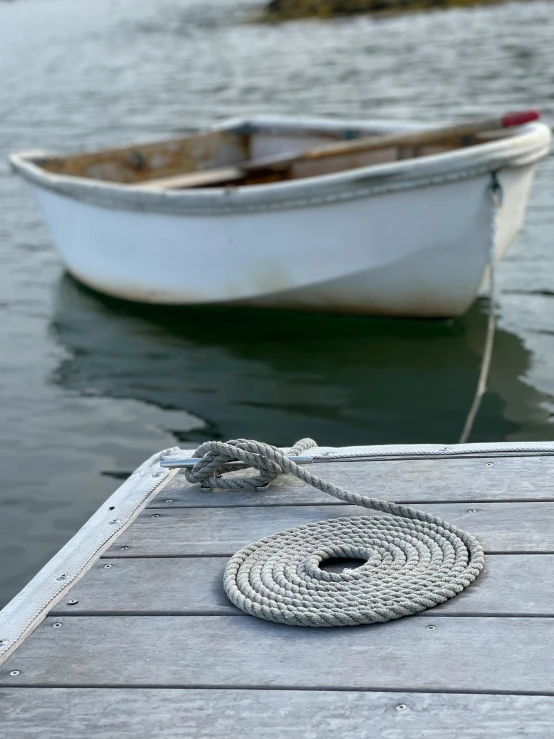 a small boat tied to a dock near a rope