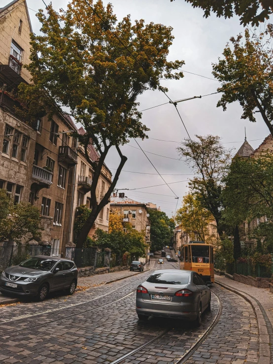 an image of a city street with vehicles on the cobblestone
