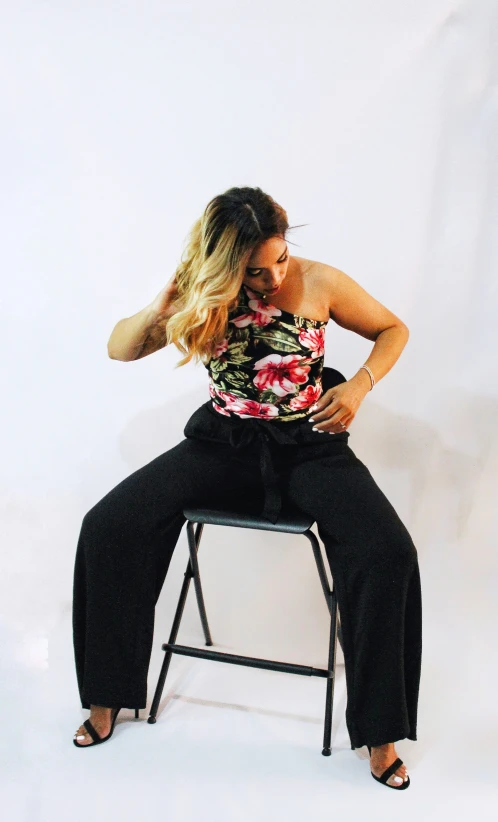 the woman sits on the stool in black pants