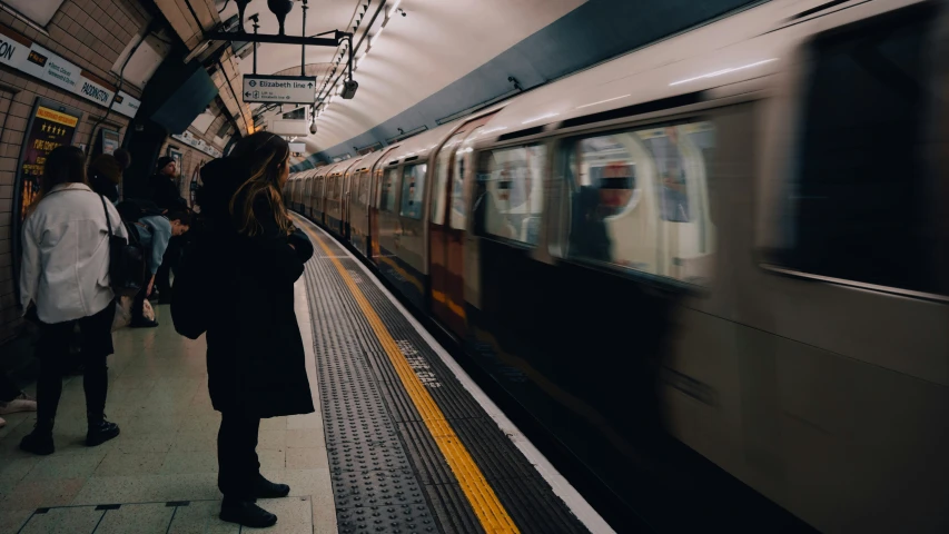 a subway with people standing next to a train