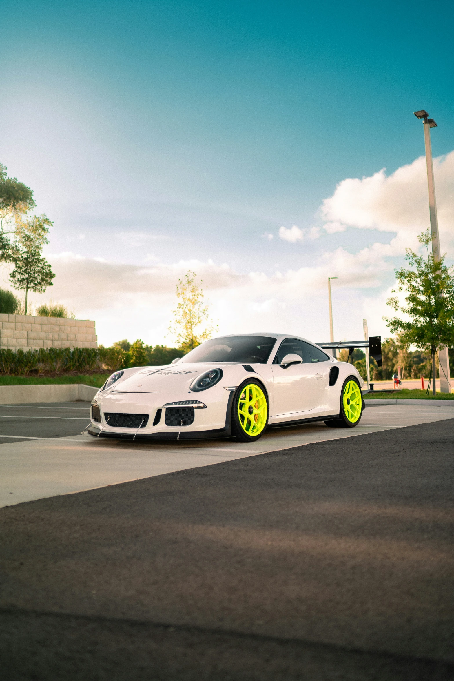 a white car with yellow rims on the street