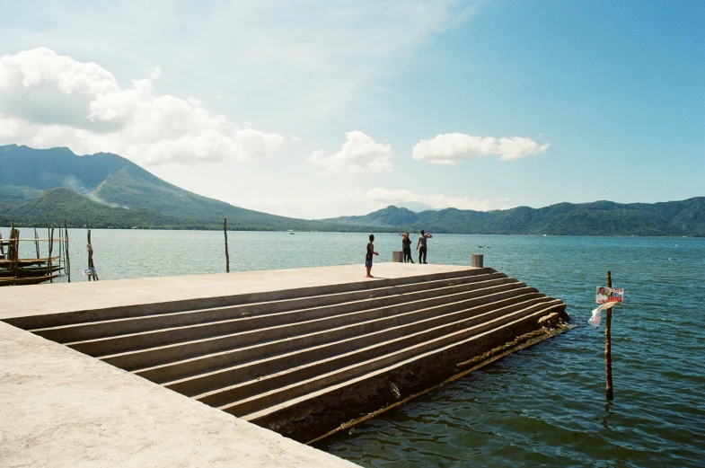 people walking on the pier over a large lake