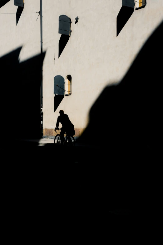 a person riding their bike in the shadows