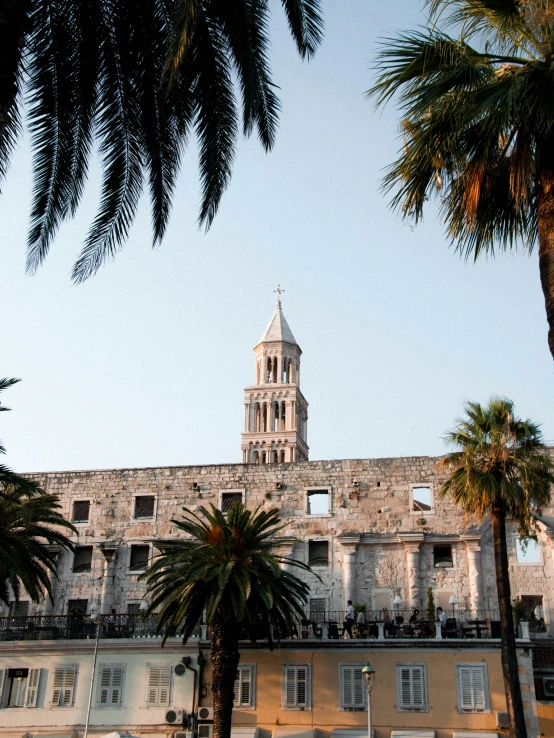 a church building sits under palm trees at the end of a walkway