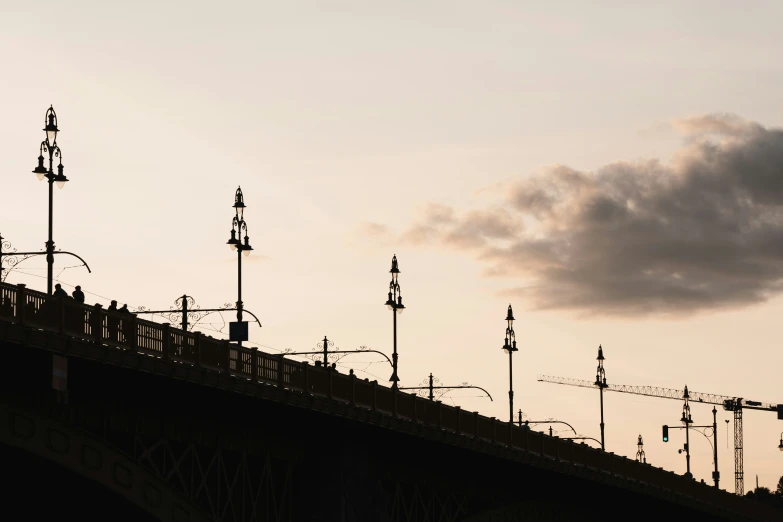 clouds, street lights and traffic lights along side a bridge