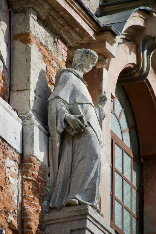 statue standing in front of a red building