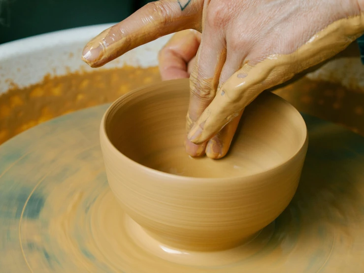 a person is creating an object on a pottery wheel