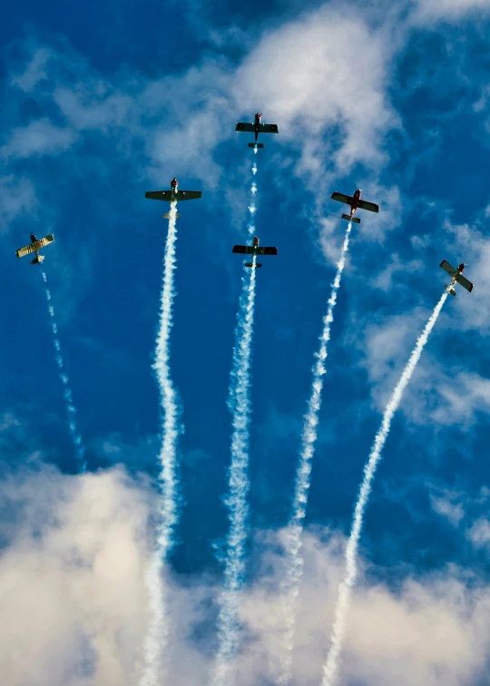 airplanes flying close together in the sky and leaving smoke trails behind them