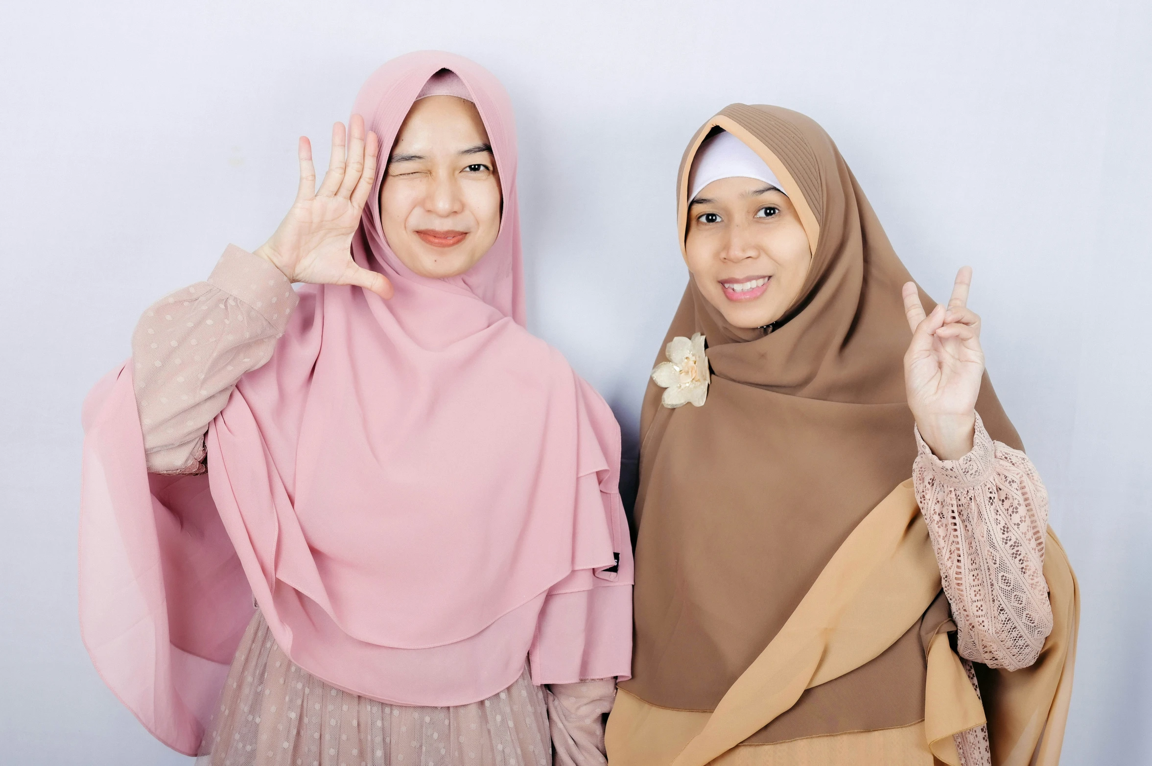 two women wearing head scarves giving the peace sign