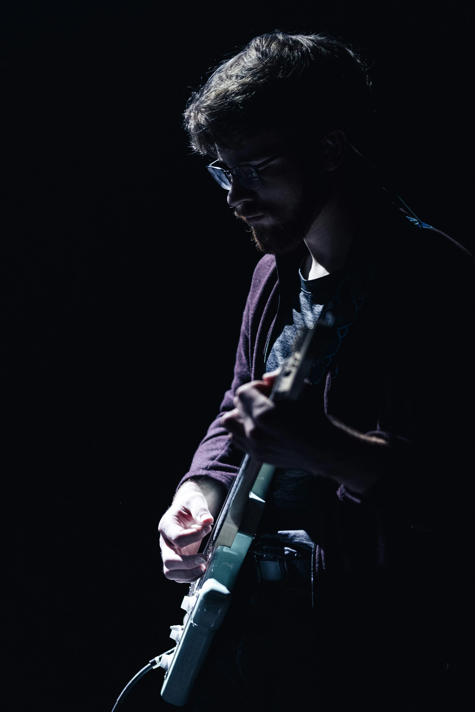 a close up of a person playing guitar in the dark