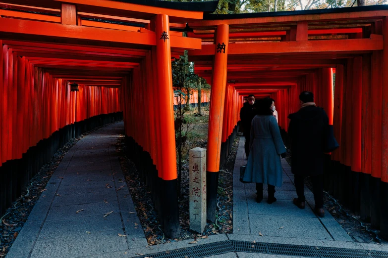 people walk around in a large tunnel of orange arches