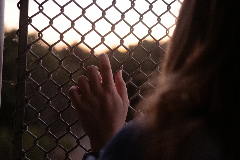 a girl touching the hand on a chain linked fence