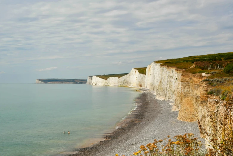 a long white beach next to a cliff