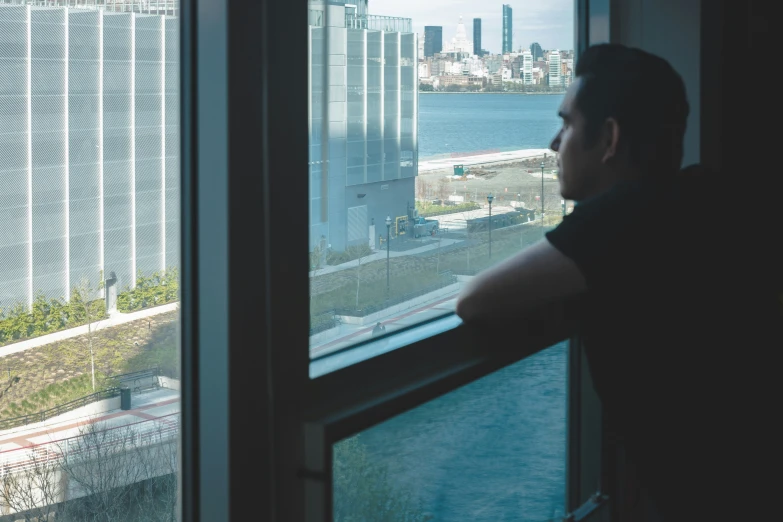 man standing in a large room looking out at a city