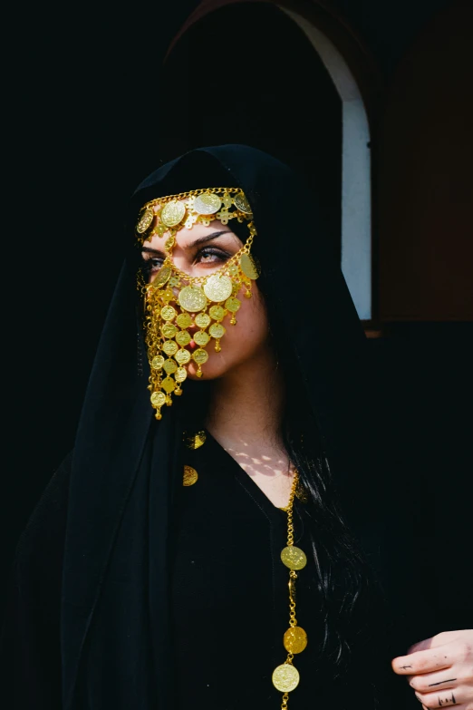 a woman in a black head scarf and gold coins