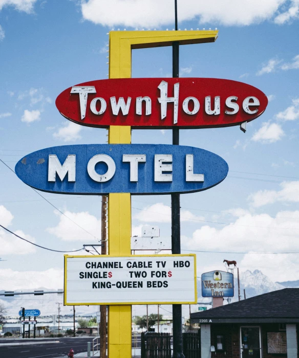 two motel signs on a yellow and red pole