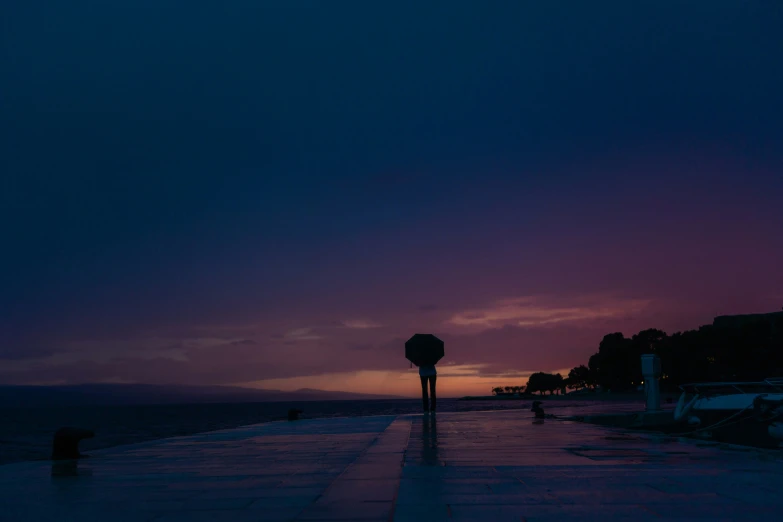 the sun setting on the water and some streetlights