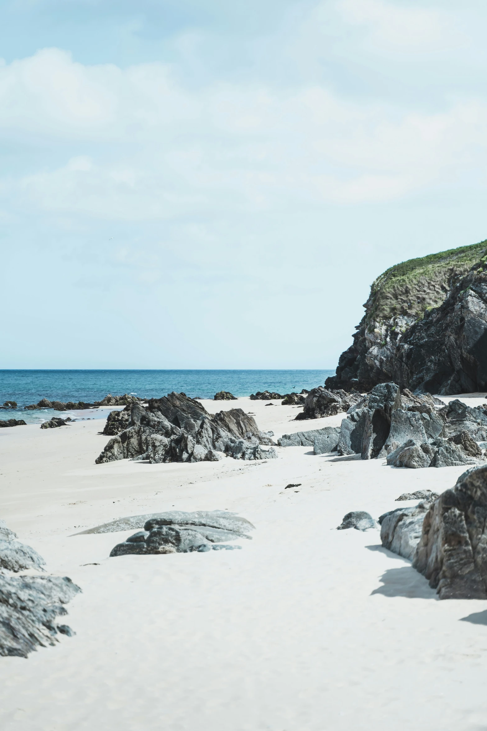 an empty white sand beach with sea stacks