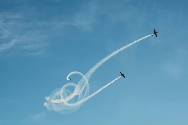 two airplanes are leaving trails in the blue sky